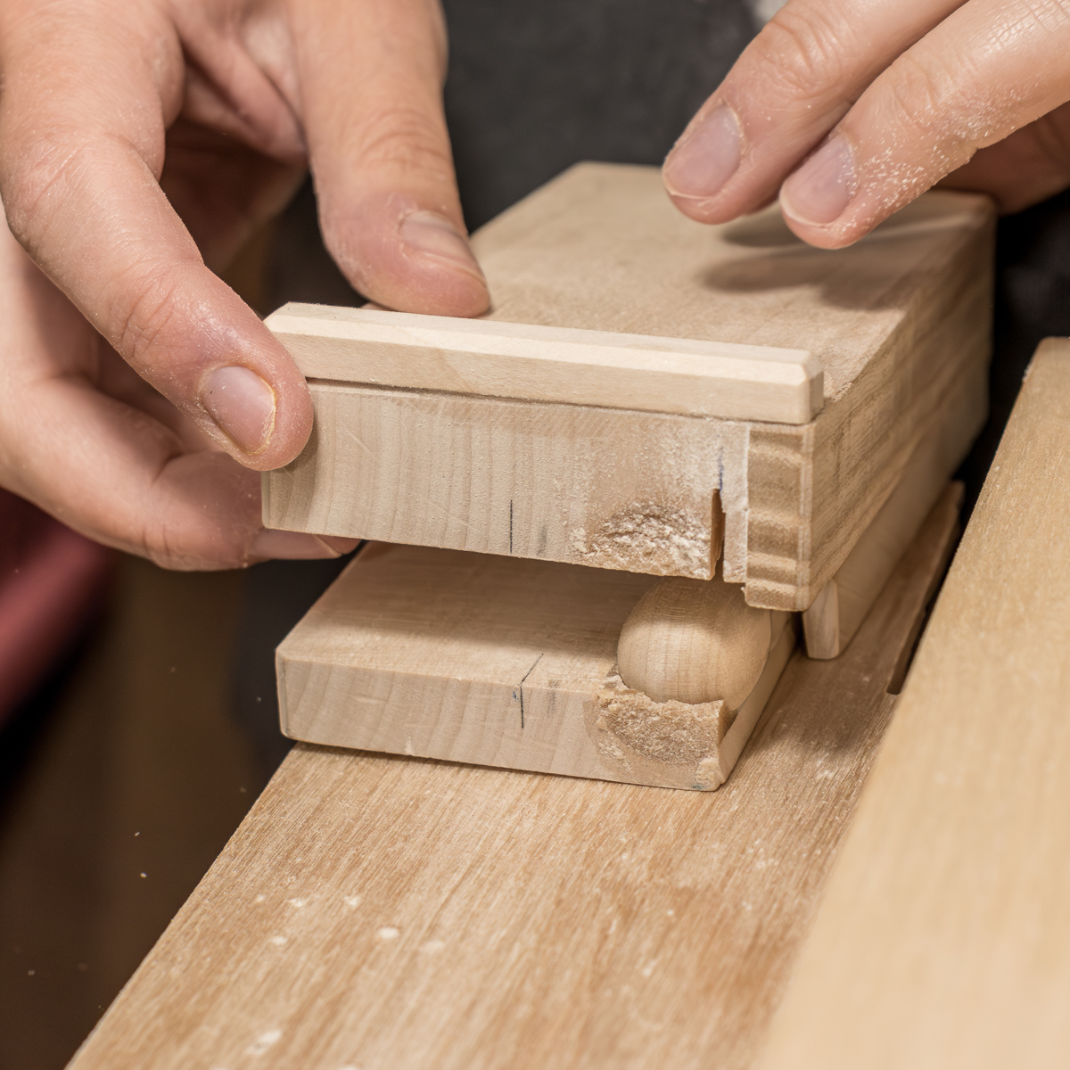 Selbstgebaute Vorrichtungen schützen die Hände und helfen uns dabei, die kleinen Teile passgenau für den Anschnitt an der Feinsäge zu positionieren.